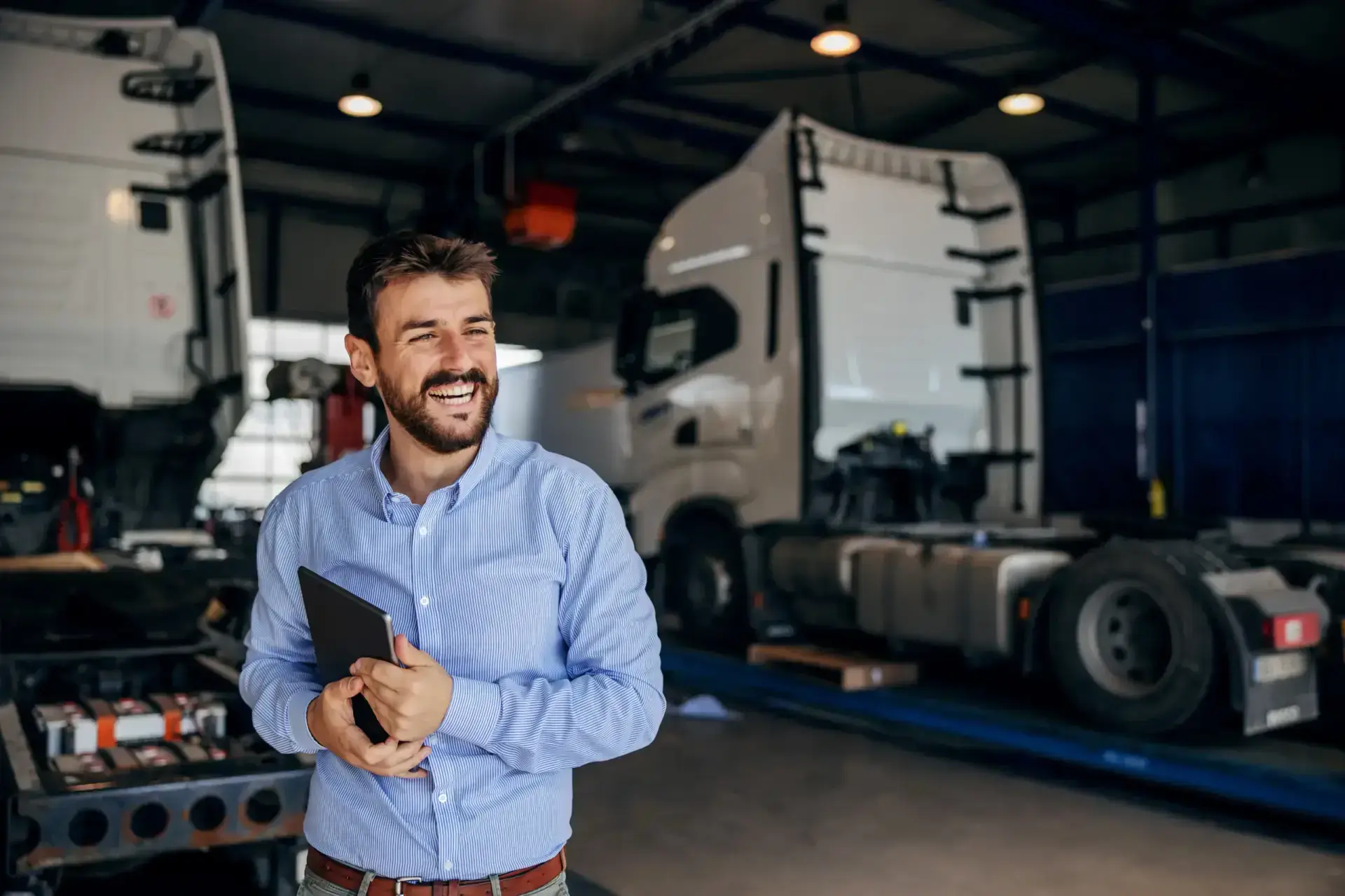 Diesel shop owner reviewing operations inside a heavy-duty truck repair bay