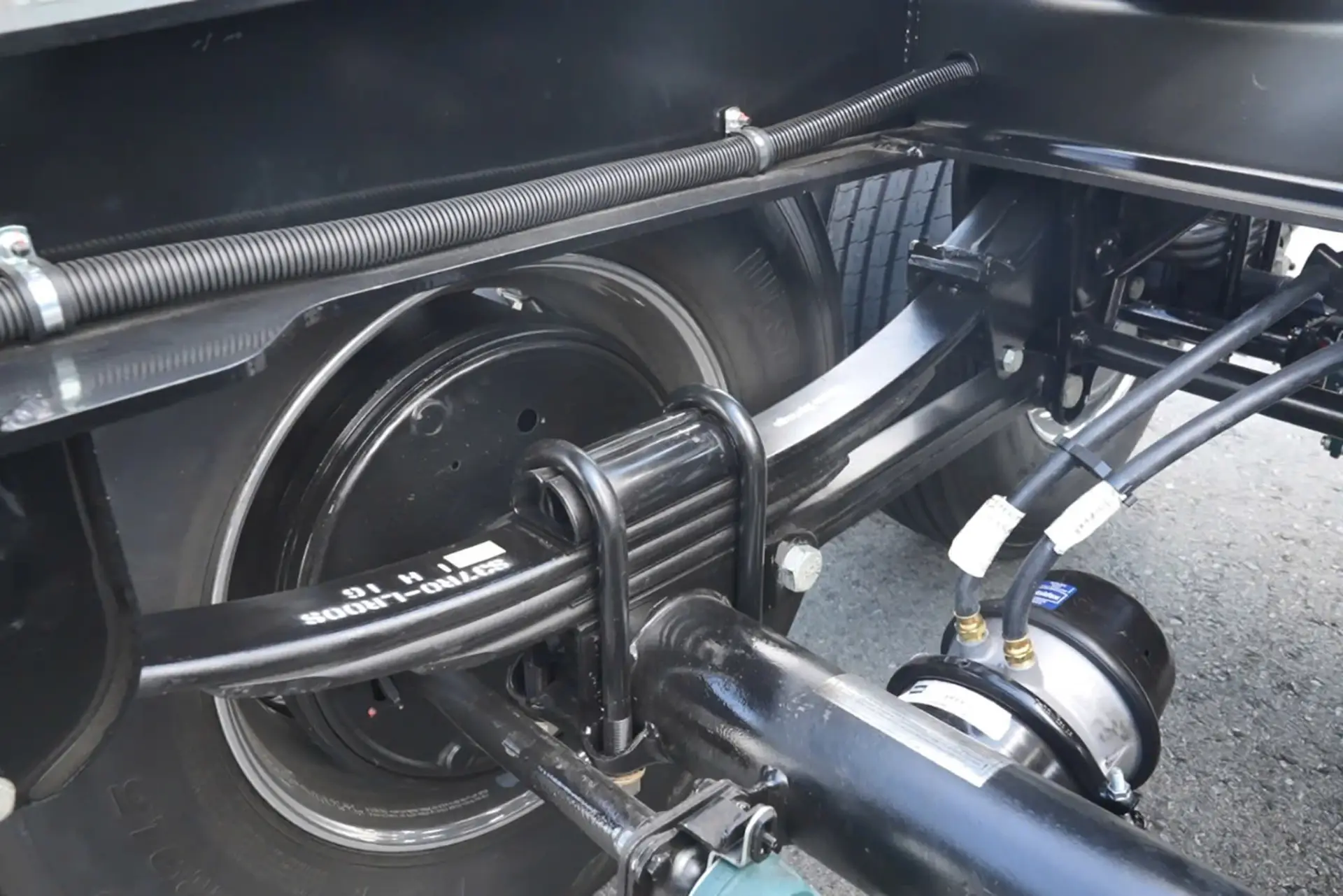 Mechanic inspecting flatbed trailer suspension system leaf springs and air bags